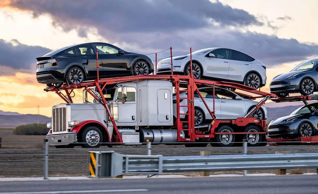 Car carrier truck transporting vehicles cross-country at sunset